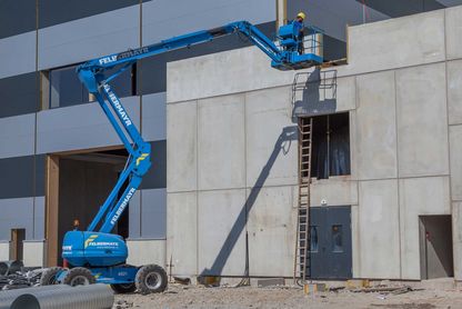 blaue Hebebühne im Einsatz auf einer Baustelle