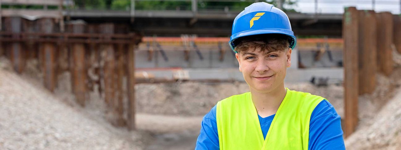 Lehre als Tiefbauer: Ein Lehrling lächelt auf der Baustelle in die Kamera