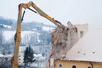 Kran mit Sortiergreifer bei Abbrucharbeiten eines alten Gebäudes