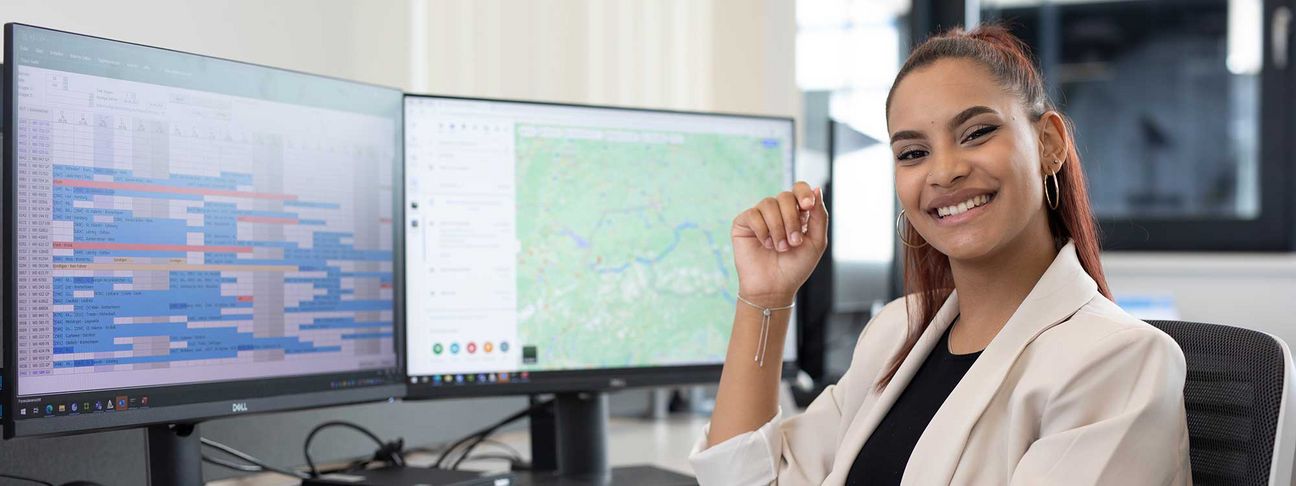 Lehre als Speditionskauffrau: Ein Lehrling sitzt vor dem Computer und lächelt in die Kamera