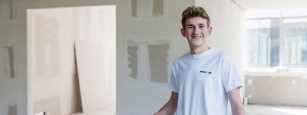 Lehre als Stuckateur und Trockenbauer: Ein Lehrling lächelt auf der Baustelle in die Kamera