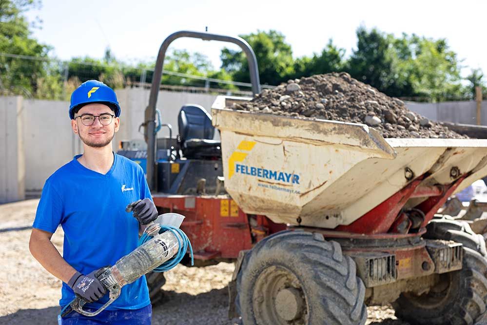 Lehre als Betonbauer: Ein Lehrling steht vor einem Dumper auf einer Baustelle