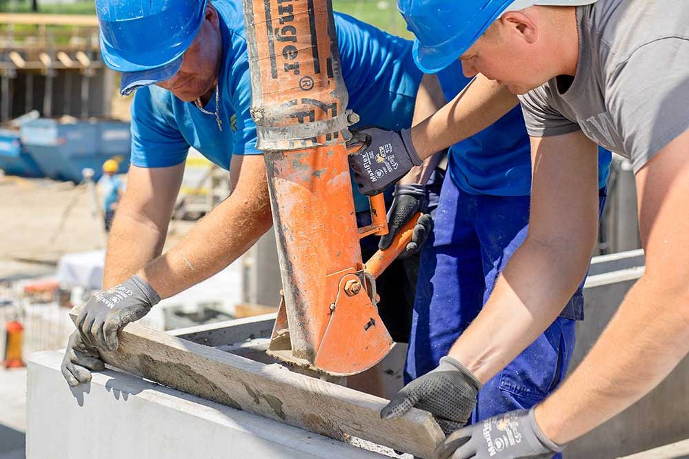 3 Bauarbeiter füllen mit einer Betonpumpe Beton in die Schalung