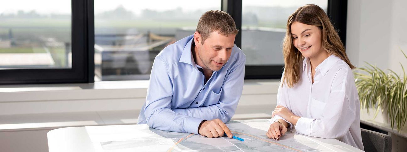 Lehre als Bautechnische Assistenz: Ein Mitarbeiter erklärt einem Lehrling einen Plan im Büro