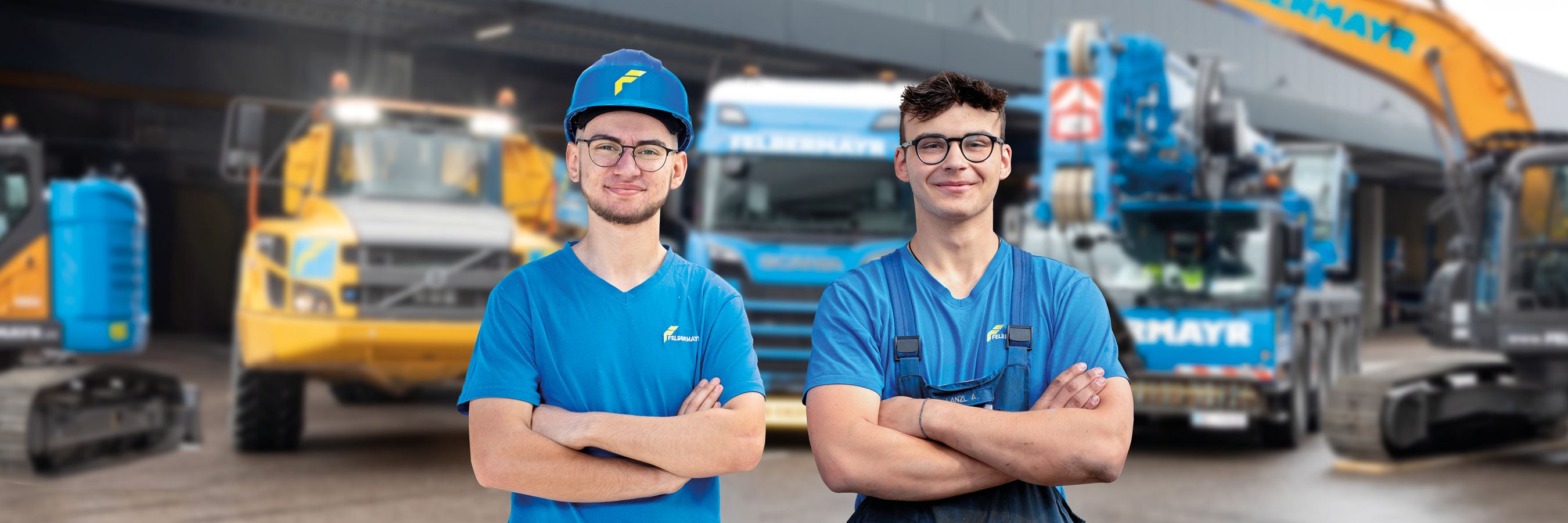 2 Lehrlinge stehen mit verschränkten Armen lachend vor Maschinen in der Werkstatt in Wels